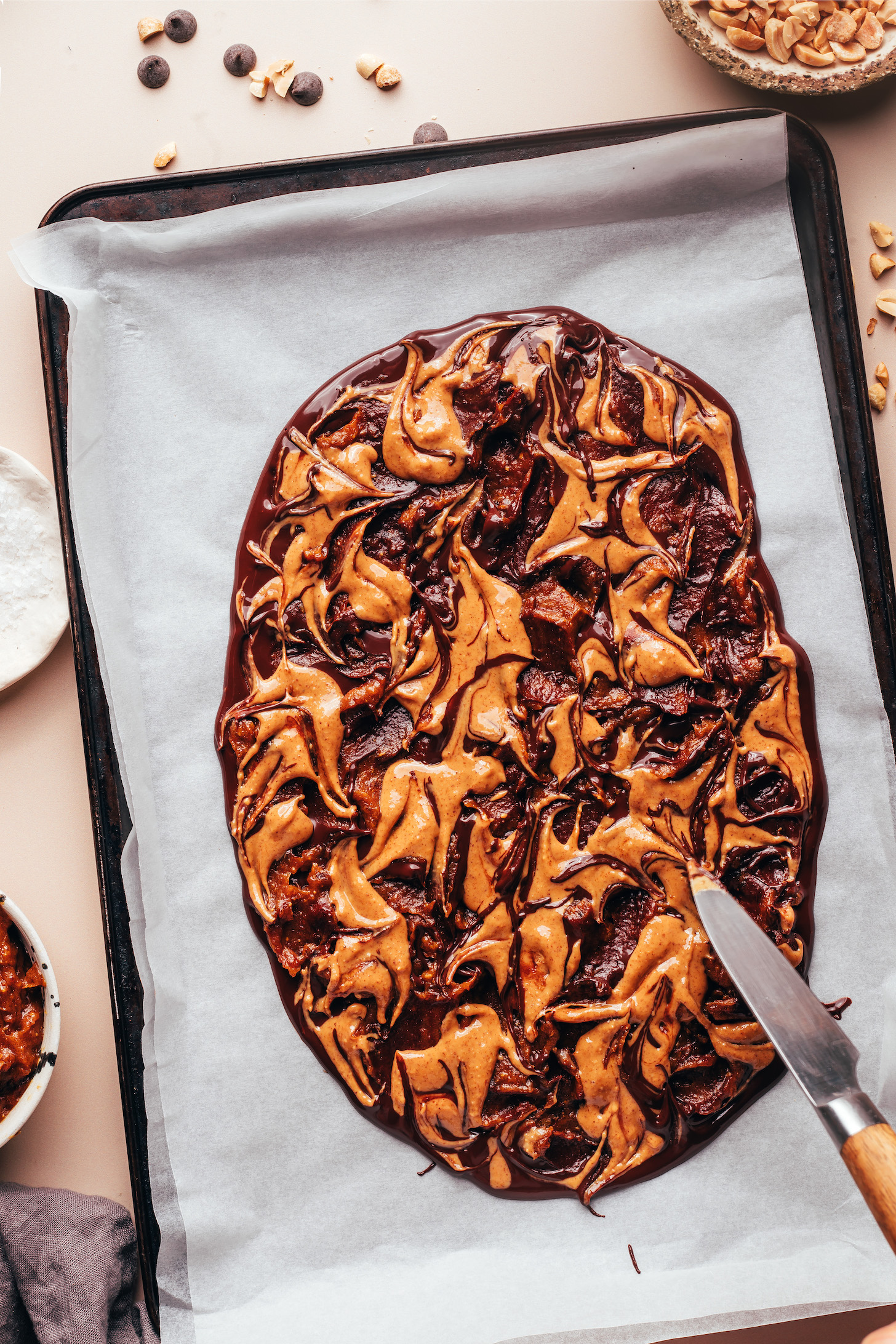 Using a knife to swirl date caramel and peanut butter into melted chocolate