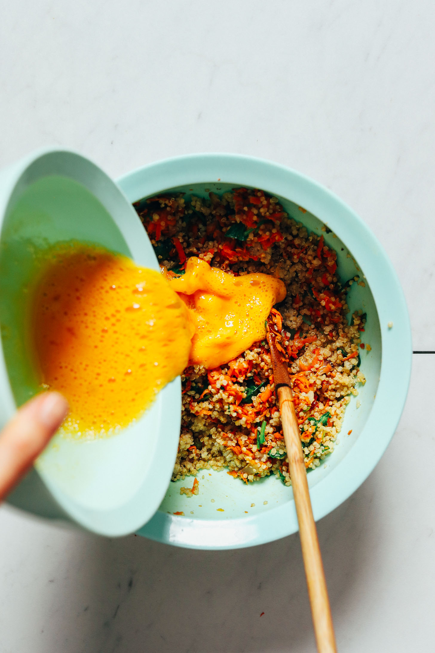 Pouring whisked eggs into the quinoa and vegetable mixture as a binder