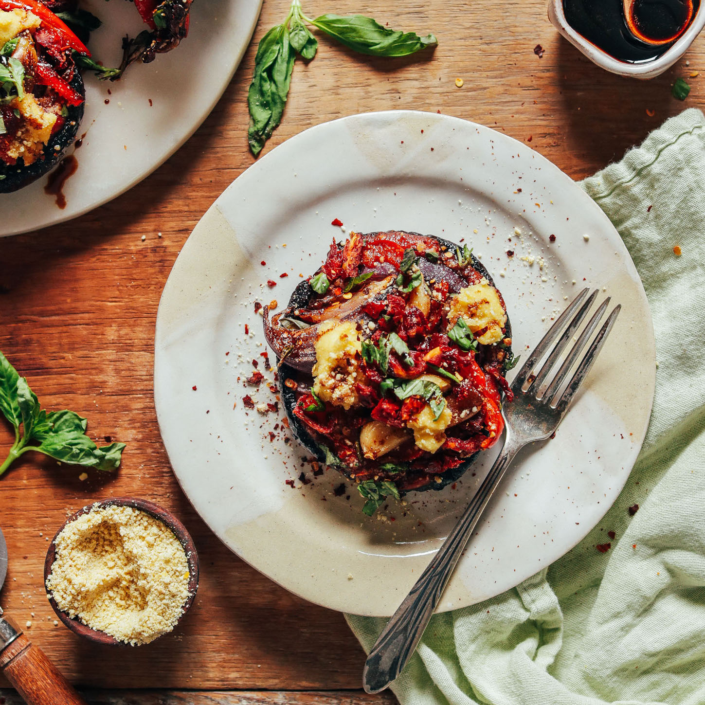 Plate with a grain-free Balsamic Portobello Pizza beside vegan parmesan, fresh basil, and balsamic reduction