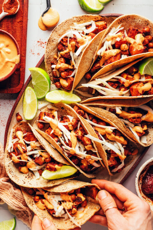 Reaching in to grab a sweet potato chickpea taco from a platter