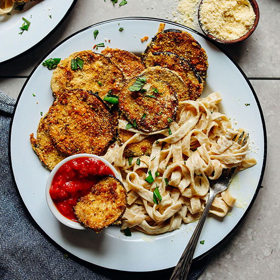 Plate of Crispy Gluten-Free Eggplant Parmesan alongside fettucine noodles and marinara