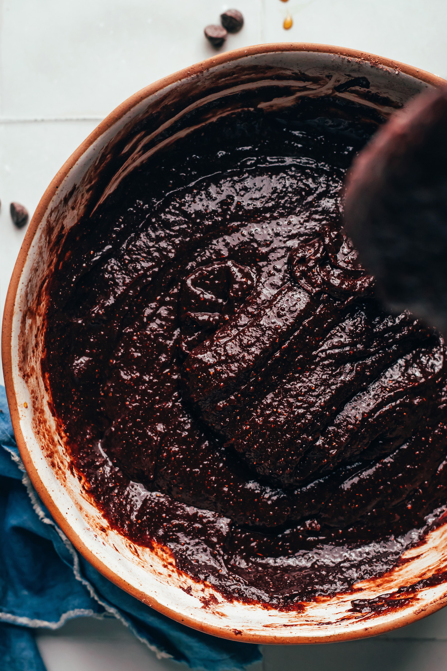 Brownie batter drizzling from a spoon into a mixing bowl