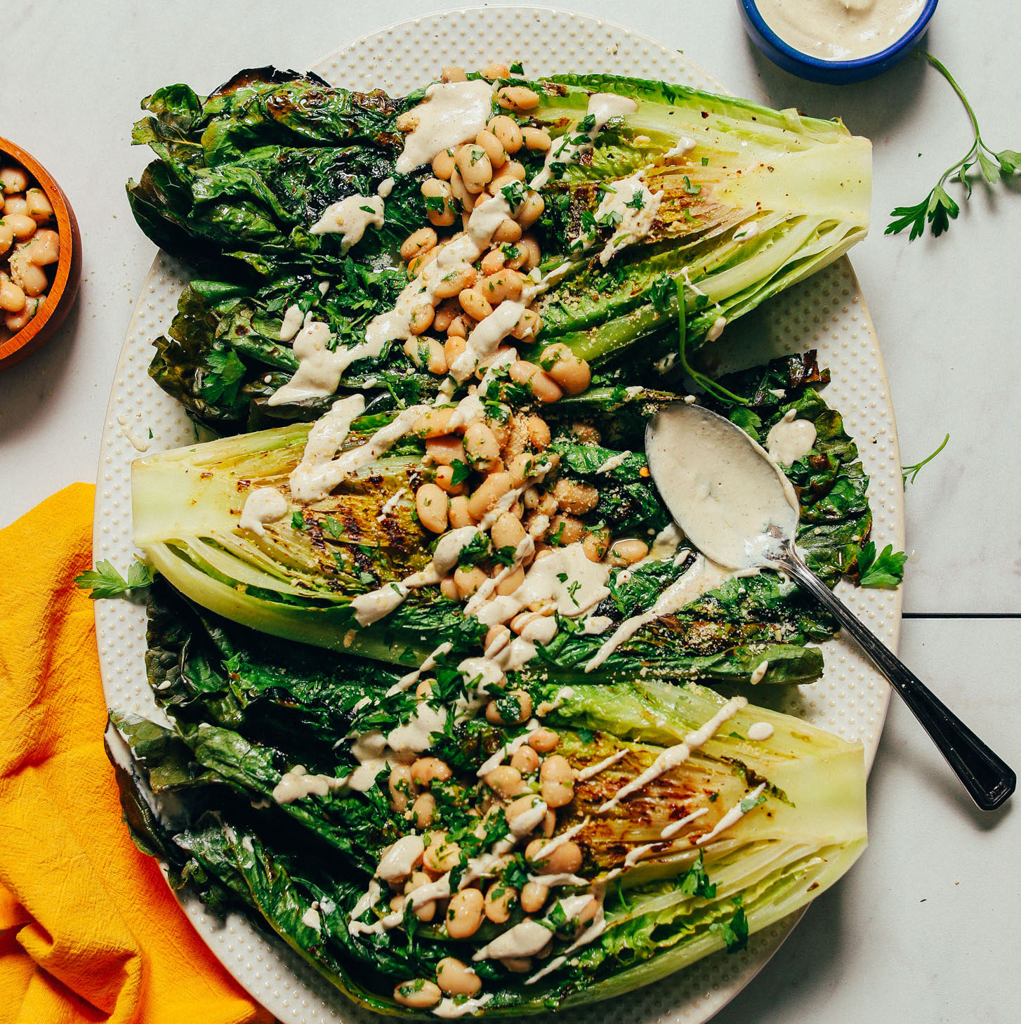 Platter of Grilled Romaine Salad topped with Lemon Herbed Beans and a drizzle of vegan Caesar Dressing