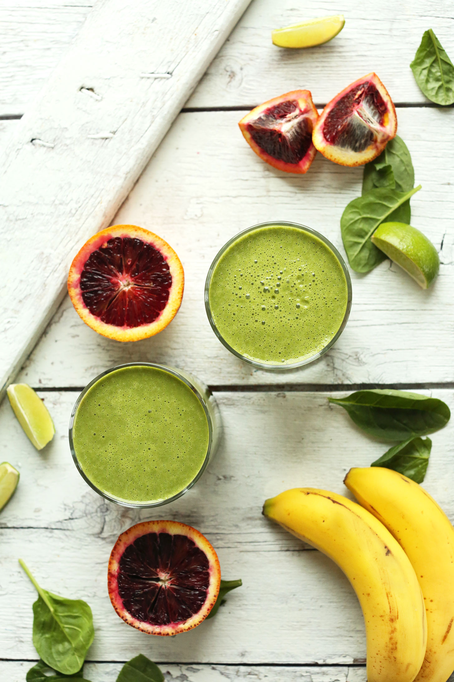 Two glasses of vegan Blood Orange Green Smoothie made with blood oranges, lime, spinach, and bananas