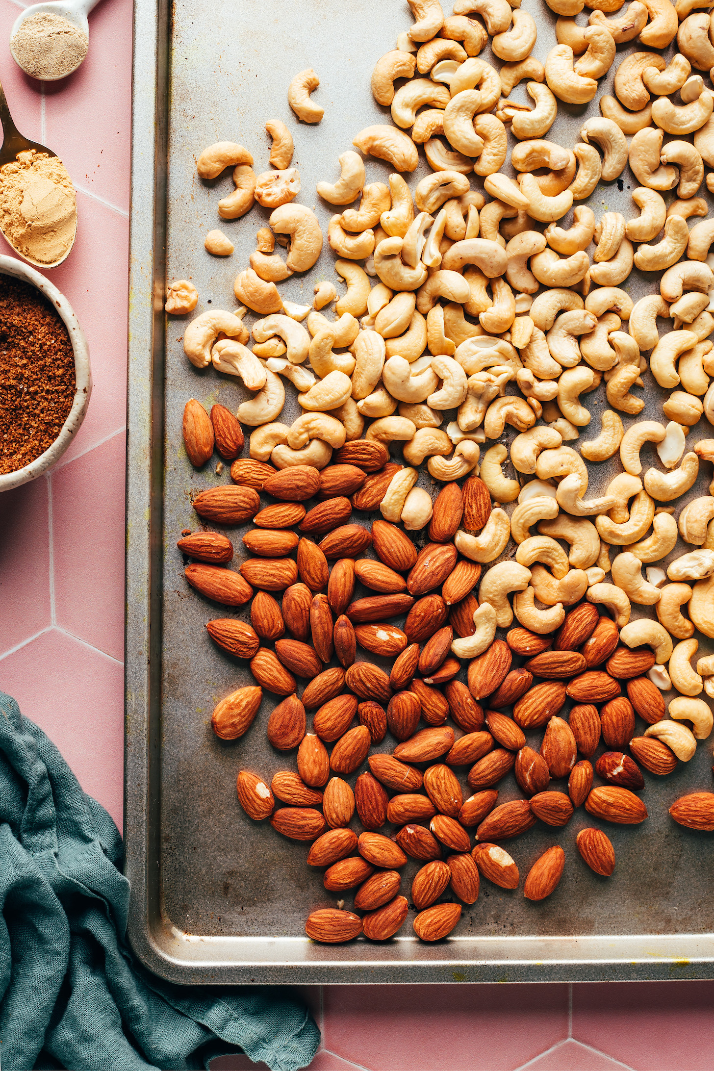 Raw almonds and cashews on a bare baking sheet