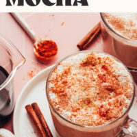 Cinnamon stick and cayenne next to a mug of our creamy homemade mayan mocha latte