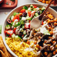 Drizzling a creamy tahini sauce over a vegan nourish bowl