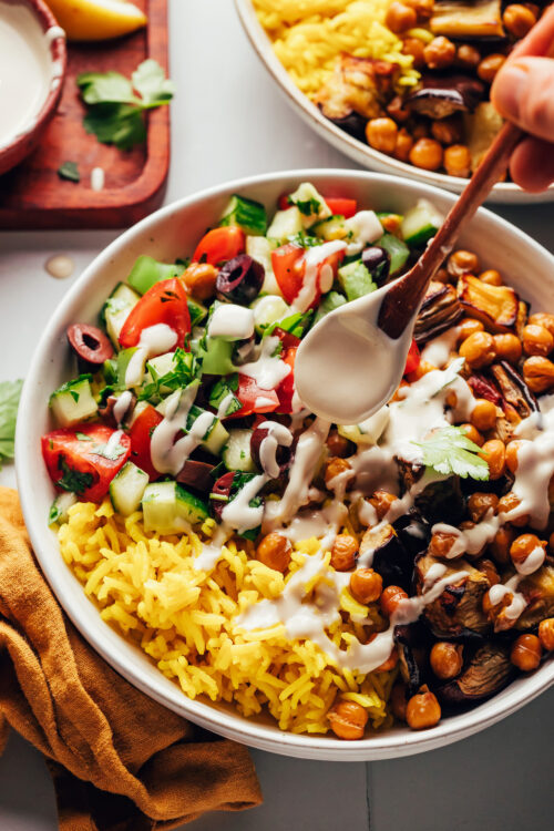 Drizzling a creamy tahini sauce over a vegan nourish bowl