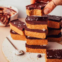 Holding a no-bake peanut butter cup bar over a stack of more bars