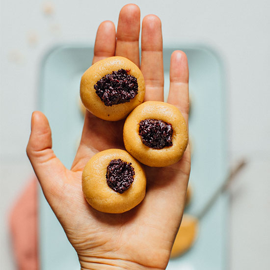 Holding three No-Bake Peanut Butter Thumbprint Cookies over a tray