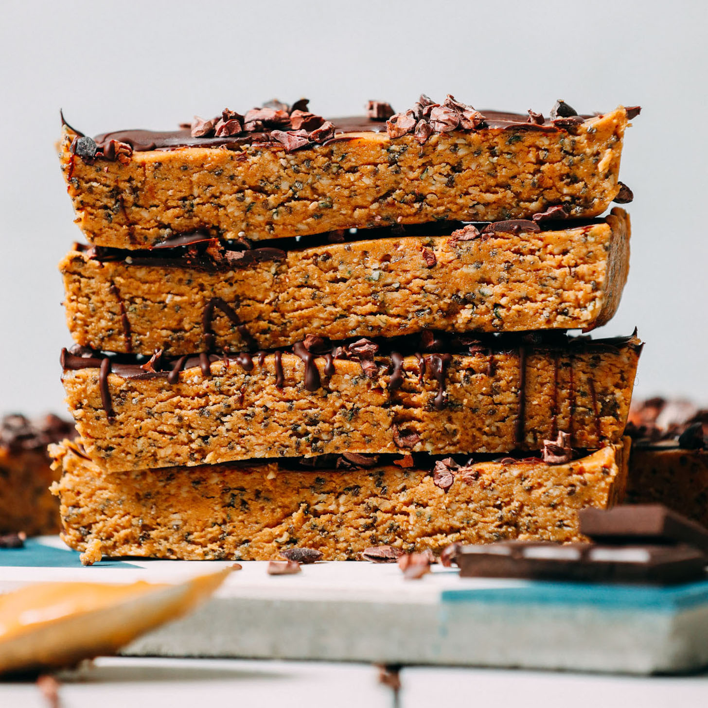 Dark chocolate and a spoonful of peanut butter resting beside homemade Peanut Butter Protein Bars