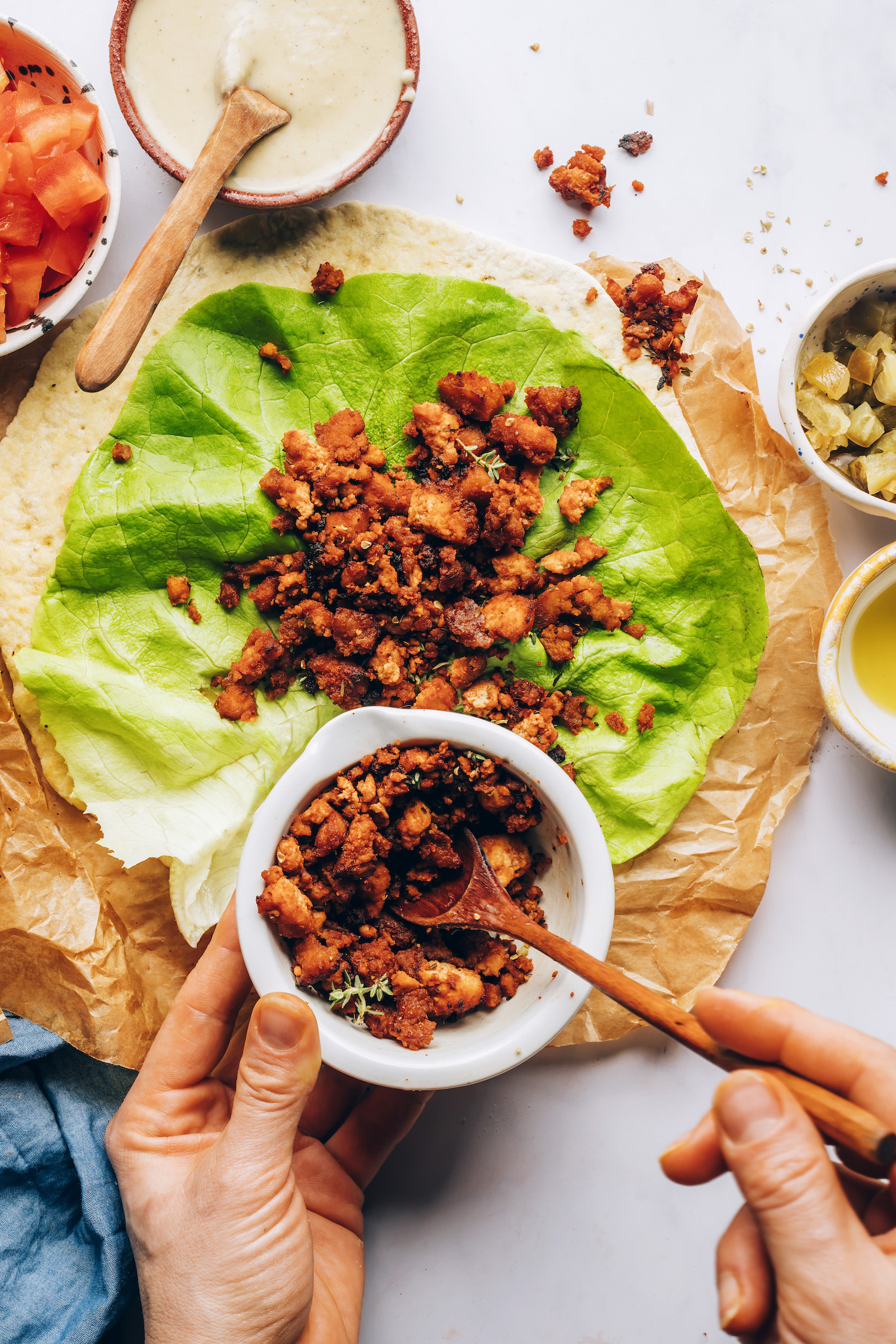 Using a spoon to add Italian Herb Baked Tofu over a lettuce leaf