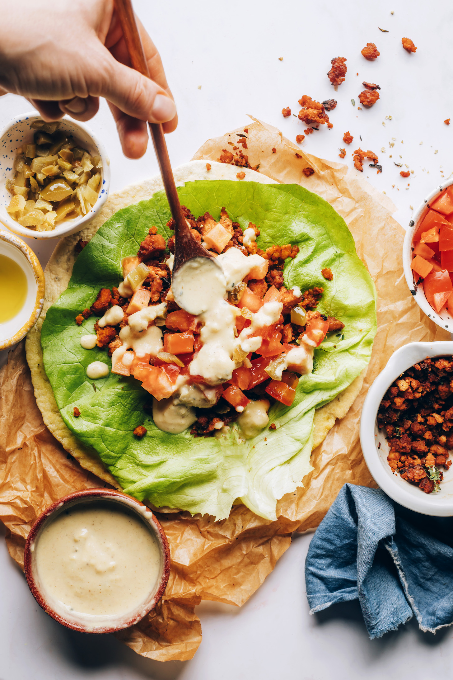 Using a spoon to drizzle hummus sauce over a wrap