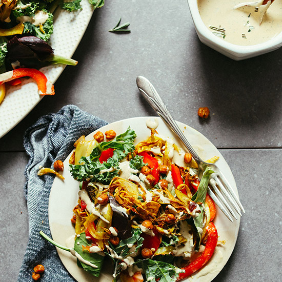 Plate of our delicious Roasted Fennel Salad with edges of the salad platter and bowl of dressing in the corners