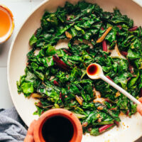 Adding tamari into a pan of sautéed swiss chard