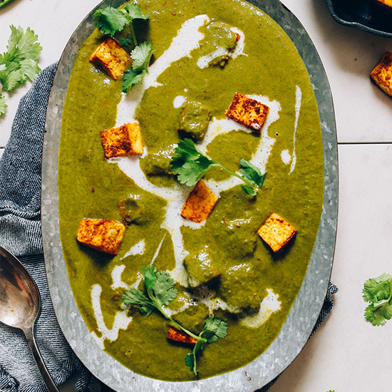 Metal tray filled with Vegan Palak Paneer with cubes of tofu