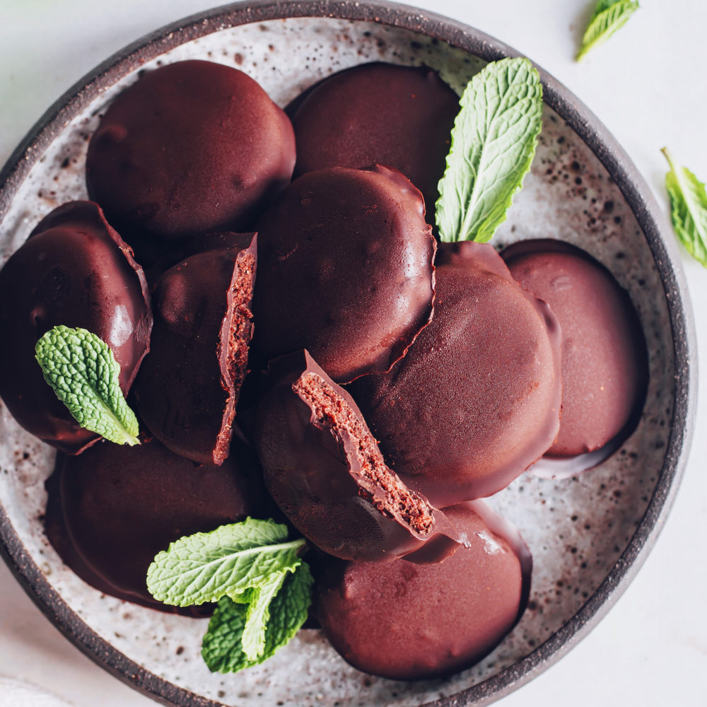 Plate piled high with thin mint cookies and fresh mint leaves