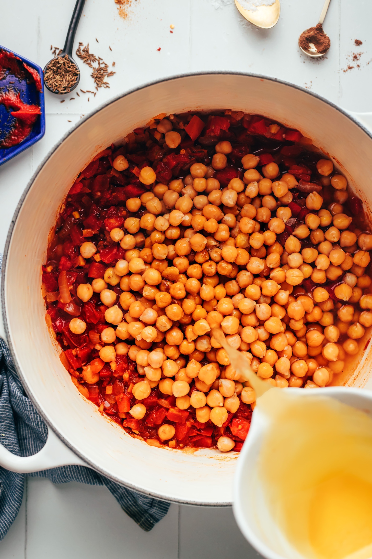 Pouring vegetable broth over chickpeas in a pot